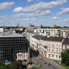 Widok na miasto z budynkami mieszkalnymi i biurowymi. W tle wieże kościołów. Ceny działek budowlanych w takich lokalizacjach są wysokie.