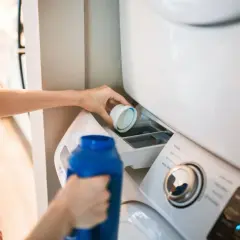 Dłoń wlewa płyn do prania do szufladki pralki. Właściwe miejsce, gdzie wlać płyn do prania, jest kluczowe dla czystości ubrań.