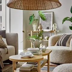 Przytulny salon w stylu skandynawskim z wygodną kanapą, puszystym fotelem i drewnianym stolikiem kawowym.
