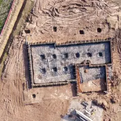 Fundamenty domu w trakcie budowy, przygotowane do zalania betonem. Widać zbrojenie i folię izolacyjną. Dobre odwodnienie domu to klucz do jego trwałości.