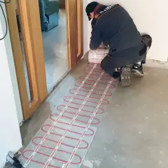 Instalator montuje matę grzewczą, przygotowując podłogę do komfortowego ogrzewania. To inwestycja w przyszłość, która obniży koszt ogrzewania podłogowego.