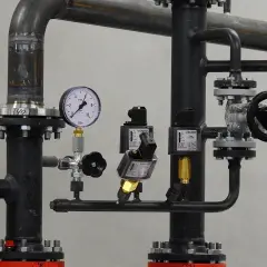 Fragment instalacji przemysłowej, prawdopodobnie w hydroforni. Widoczne rury, zawory, manometr i elektrozawory.