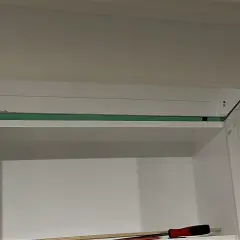 Montaż ukrytych drzwi w regale. Widoczne elementy konstrukcyjne i narzędzia.
