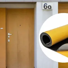 Ocieplenie drzwi wewnętrznych: rolka materiału izolacyjnego z żółtą warstwą klejącą obok drzwi wejściowych.