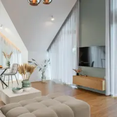 Przytulny salon z sofą w kolorze kremowym, stołem i krzesłami, ozdobiony trawami pampasowymi.