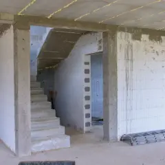 Budowa domu. Schody prowadzą do góry. Jaki otwór pod drzwi 80 cm? W tle widać drabiny i materiały budowlane.