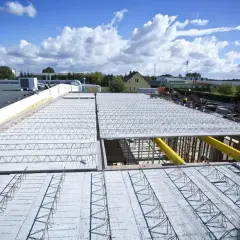 Budowa nowego stropu nad halą przemysłową. Widoczna konstrukcja zbrojeniowa i elementy stropowe.
