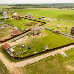 Działka z domami w budowie i gotowymi, otoczona płotem. Widać drogi dojazdowe, co sugeruje służebność drogi problemy.