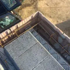 Szalowanie stropu z bloczków betonowych i zbrojenia. Obok stoi samochód.