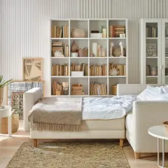 Jak pogodzić salon z sypialnią? Rozkładana sofa, regały z książkami i dekoracje tworzą przytulną przestrzeń.
