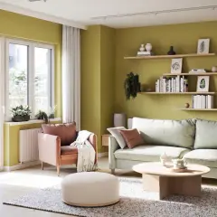 Jasnozielone, modne kolory ścian tworzą przytulną atmosferę w salonie z pastelową sofą i fotelem.