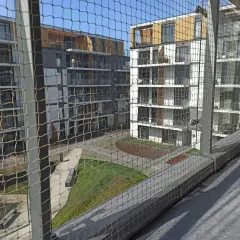 Nowoczesne bloki mieszkalne z balkonami, zabezpieczone siatką. Zastanawiasz się, ile kosztuje montaż siatki na balkonie?