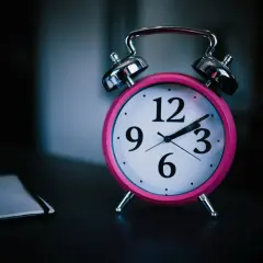 Różowy budzik na stoliku przypomina o ciszy nocnej w bloku. Zegar wskazuje późną godzinę, gdy wszyscy powinni już spać.