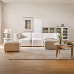 Jasny, monochromatyczny salon z wygodną sofą, pufą i stolikiem kawowym.