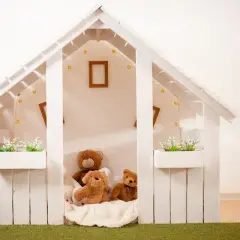 Jak zbudować domek dla dzieci? Biały, drewniany domek z pluszakami i lampkami, idealny do zabawy.