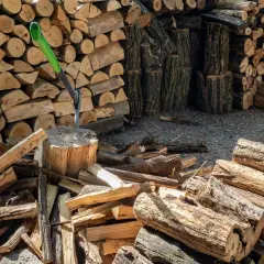 Stos drewna opałowego, siekiera wbita w pień. Wiele polan, przygotowanie do zimy. Cena drewna opałowego może być wysoka.