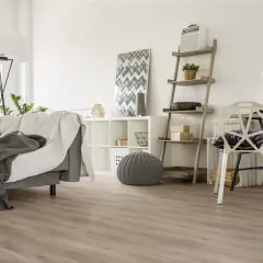Jasne, oto propozycja:

Nowoczesny salon z szarą kanapą i kocami, białą komodą i regałem. Podłoga wygląda jak panele laminowane czy winylowe.