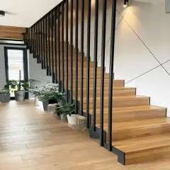 Nowoczesne drewniane schody z czarną balustradą. Zastanawiasz się, ile kosztuje zrobienie schodów? Warto rozważyć ten projekt.
