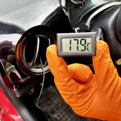 Rękawiczka w ręku trzyma termometr pokazujący 17.9°C. To część procesu samodzielnego nabijania klimatyzacji w samochodzie.