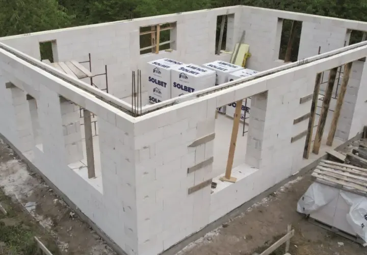 Budowa domu z bloczków z betonu komórkowego. Widoczne ściany z otworami okiennymi i drzwiowymi, materiały budowlane.
