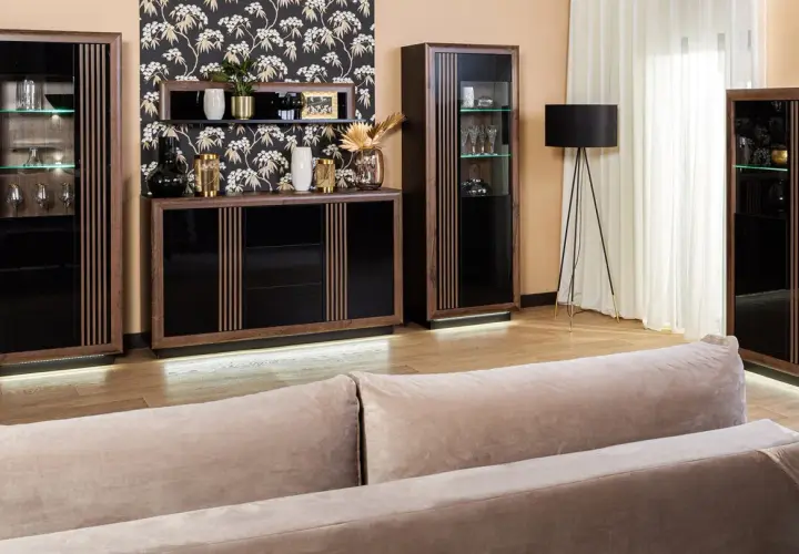 Elegancki salon z meblami z ciemnego drewna, czarnymi frontami i subtelnym oświetleniem LED.