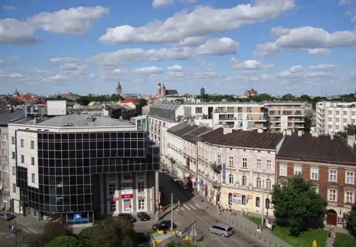 Widok na miasto z budynkami mieszkalnymi i biurowymi. W tle wieże kościołów. Ceny działek budowlanych w takich lokalizacjach są wysokie.