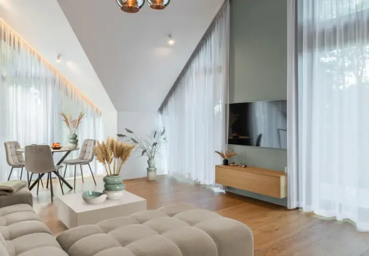 Przytulny salon z sofą w kolorze kremowym, stołem i krzesłami, ozdobiony trawami pampasowymi.