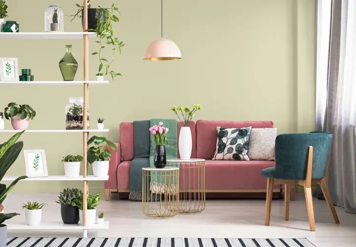 Salon z różową kanapą i zielonymi akcentami. Oliwkowa zieleń ścian tworzy spokojną atmosferę.