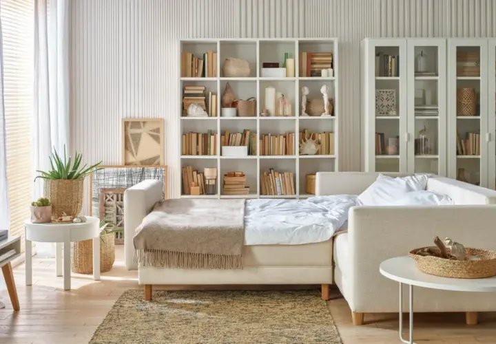 Jak pogodzić salon z sypialnią? Rozkładana sofa, regały z książkami i dekoracje tworzą przytulną przestrzeń.