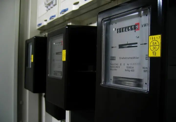 Rząd czarnych liczników energii elektrycznej, każdy z wyświetlaczem pokazującym zużycie w kilowatogodzinach.
