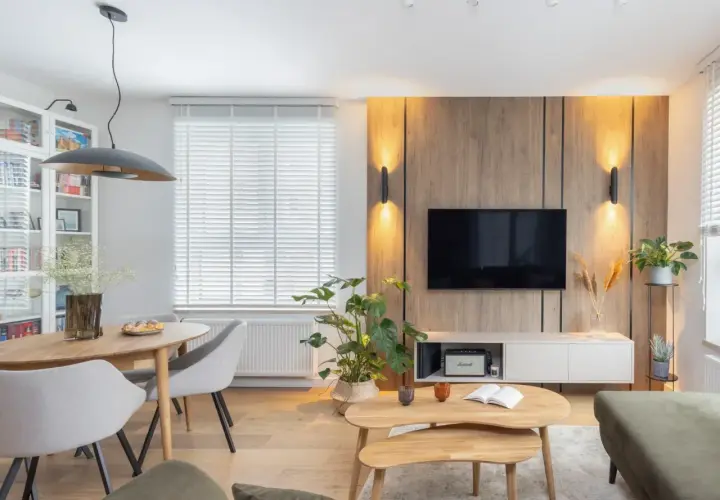 Przytulny salon inspiracje: drewniana ściana z TV, jadalnia, rośliny i wygodna sofa tworzą ciepłą atmosferę.