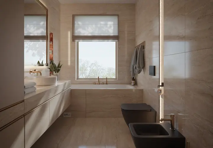 Nowoczesna łazienka z oknem na wprost drzwi, wanna, czarna miska WC i bidet, kamienne płytki, złote baterie.