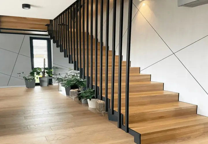 Nowoczesne drewniane schody z czarną balustradą. Zastanawiasz się, ile kosztuje zrobienie schodów? Warto rozważyć ten projekt.