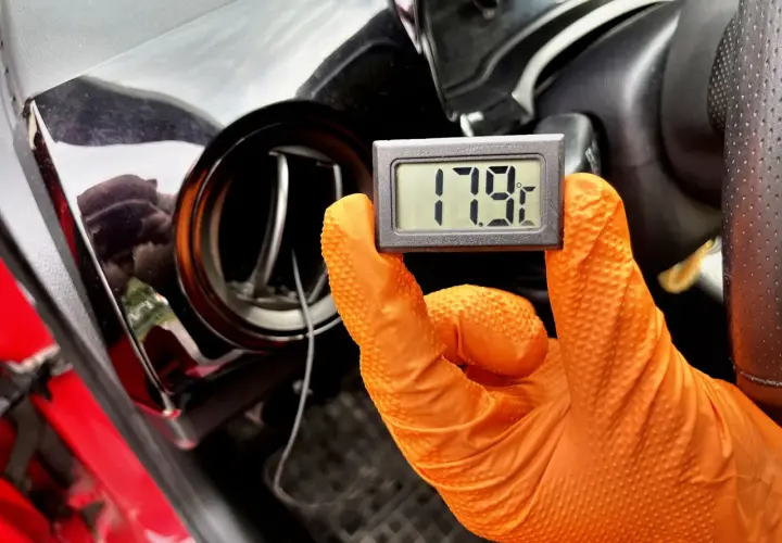 Rękawiczka w ręku trzyma termometr pokazujący 17.9°C. To część procesu samodzielnego nabijania klimatyzacji w samochodzie.
