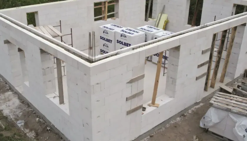 Budowa domu z bloczków z betonu komórkowego. Widoczne ściany z otworami okiennymi i drzwiowymi, materiały budowlane.