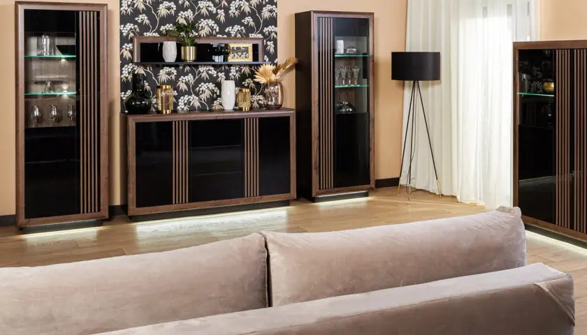 Elegancki salon z meblami z ciemnego drewna, czarnymi frontami i subtelnym oświetleniem LED.