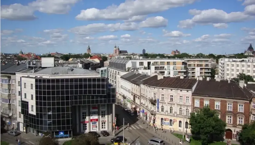 Widok na miasto z budynkami mieszkalnymi i biurowymi. W tle wieże kościołów. Ceny działek budowlanych w takich lokalizacjach są wysokie.