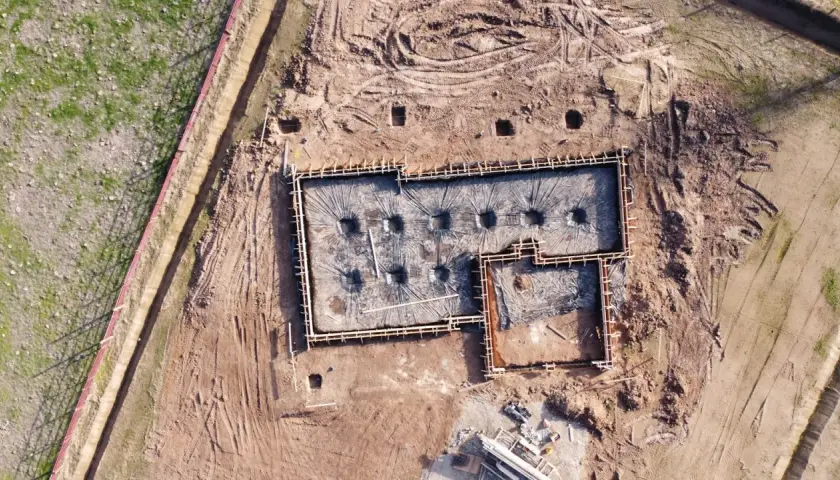 Fundamenty domu w trakcie budowy, przygotowane do zalania betonem. Widać zbrojenie i folię izolacyjną. Dobre odwodnienie domu to klucz do jego trwałości.