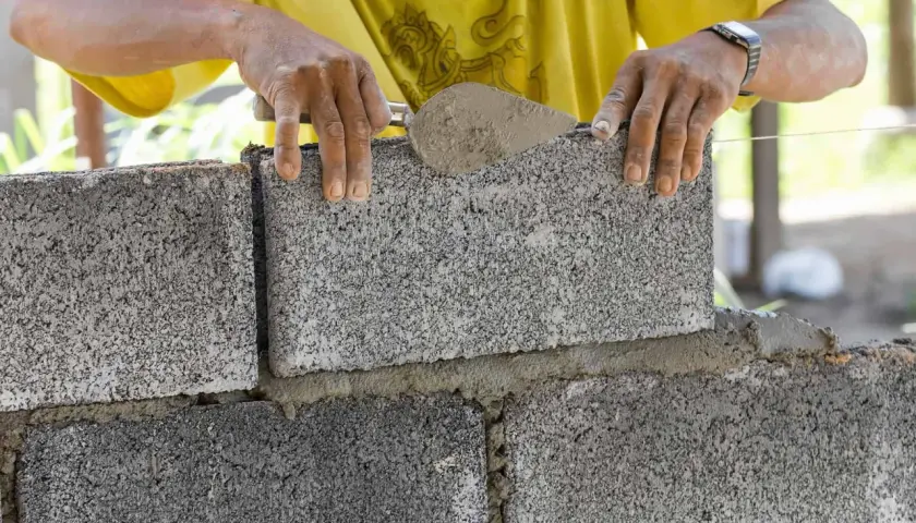 Budowniczy układa bloczki betonowe fundamentowe, tworząc solidną podstawę.