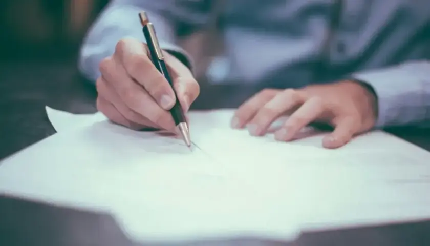 Dłoń pisze na papierze, być może notując, jak wygląda numer księgi wieczystej.