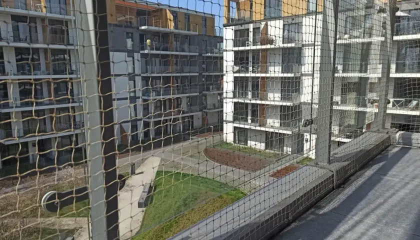 Nowoczesne bloki mieszkalne z balkonami, zabezpieczone siatką. Zastanawiasz się, ile kosztuje montaż siatki na balkonie?