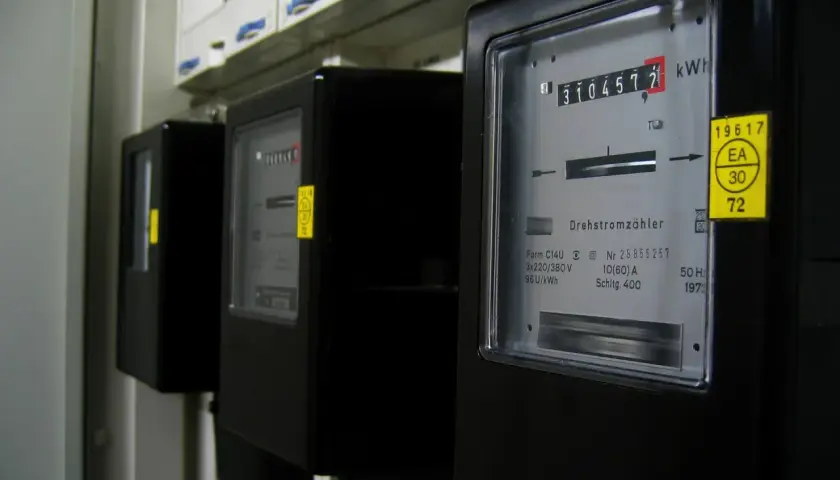 Rząd czarnych liczników energii elektrycznej, każdy z wyświetlaczem pokazującym zużycie w kilowatogodzinach.