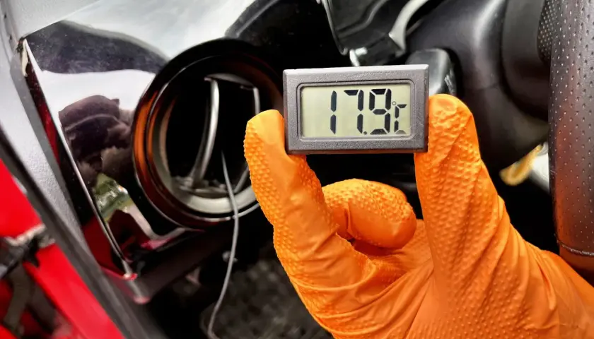 Rękawiczka w ręku trzyma termometr pokazujący 17.9°C. To część procesu samodzielnego nabijania klimatyzacji w samochodzie.