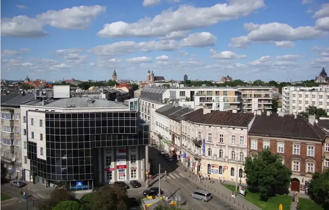 Widok na miasto z budynkami mieszkalnymi i biurowymi. W tle wieże kościołów. Ceny działek budowlanych w takich lokalizacjach są wysokie.