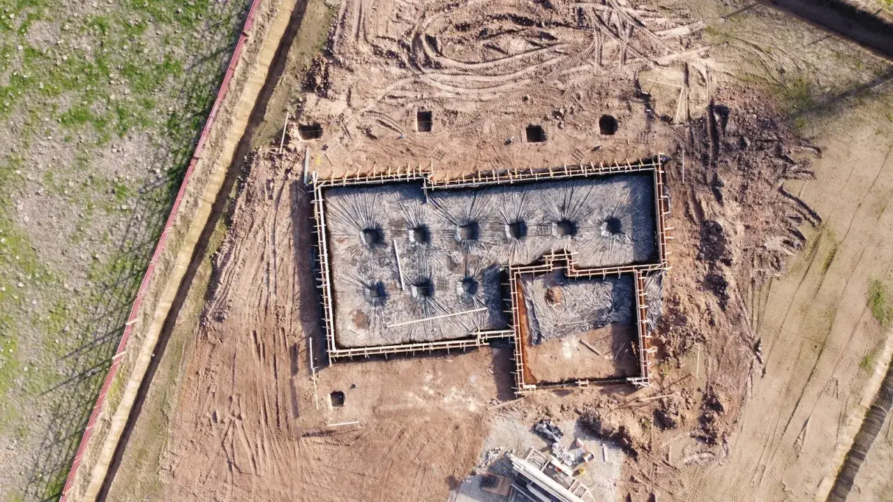 Fundamenty domu w trakcie budowy, przygotowane do zalania betonem. Widać zbrojenie i folię izolacyjną. Dobre odwodnienie domu to klucz do jego trwałości.