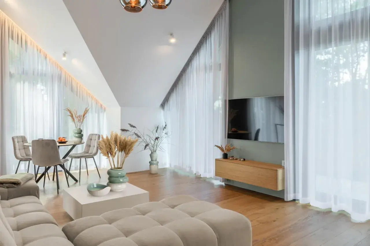 Przytulny salon z sofą w kolorze kremowym, stołem i krzesłami, ozdobiony trawami pampasowymi.