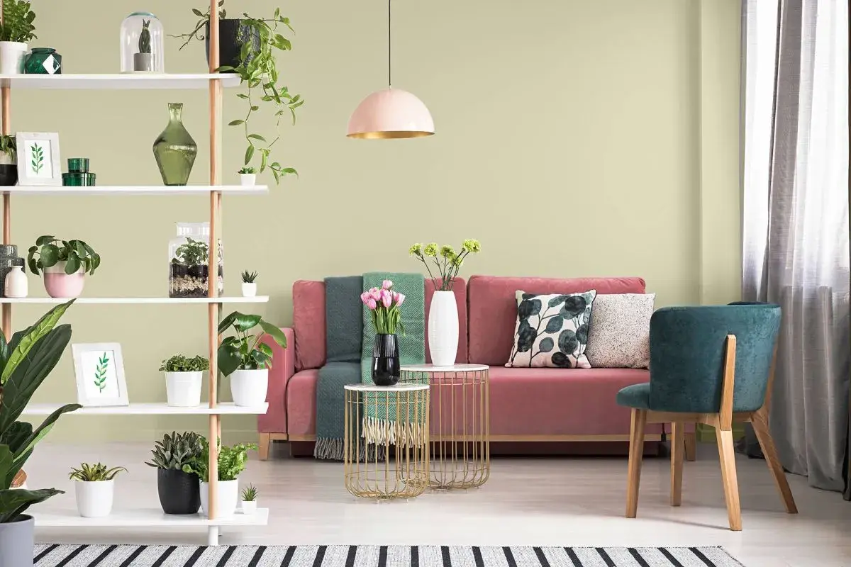 Salon z różową kanapą i zielonymi akcentami. Oliwkowa zieleń ścian tworzy spokojną atmosferę.