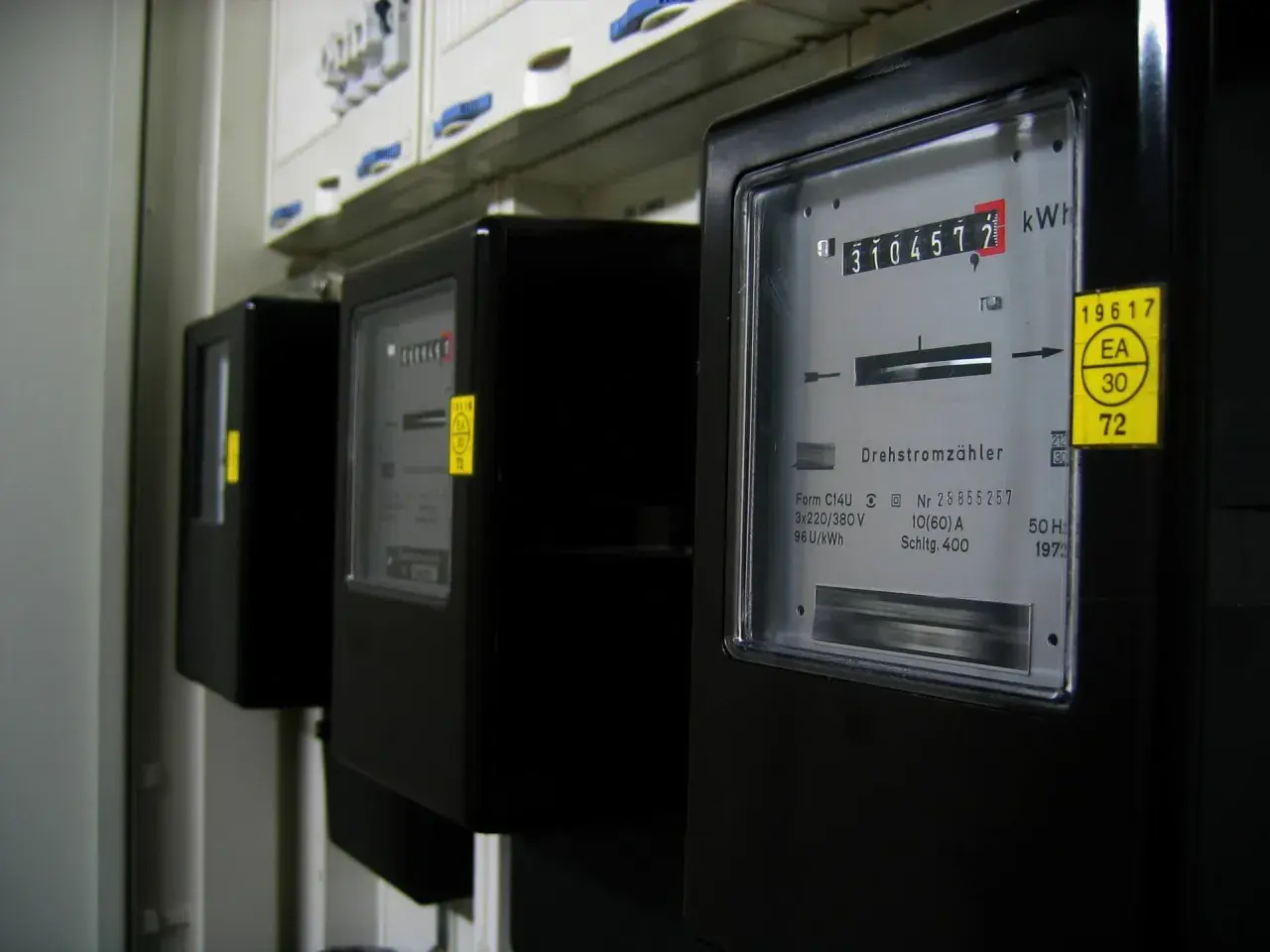 Rząd czarnych liczników energii elektrycznej, każdy z wyświetlaczem pokazującym zużycie w kilowatogodzinach.