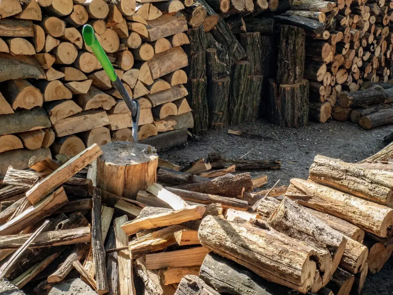 Stos drewna opałowego, siekiera wbita w pień. Wiele polan, przygotowanie do zimy. Cena drewna opałowego może być wysoka.