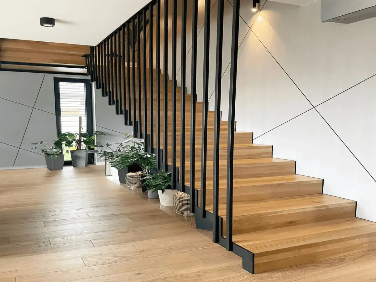 Nowoczesne drewniane schody z czarną balustradą. Zastanawiasz się, ile kosztuje zrobienie schodów? Warto rozważyć ten projekt.
